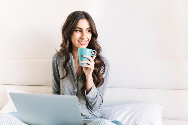 Kostenloses Foto verträumte frau mit cup und laptop