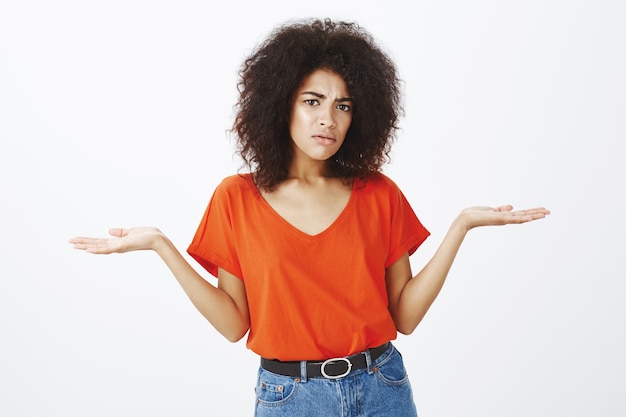 verwirrte Frau mit Afro-Frisur posiert im Studio