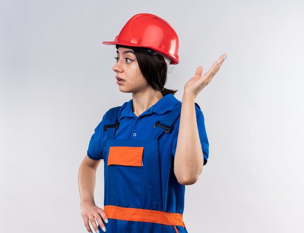 Verwirrter Blick auf die junge Baumeisterin in Uniform mit der Hand an der Seite