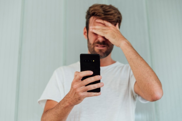 Kostenloses Foto verwirrter mann, der modernes telefon hält