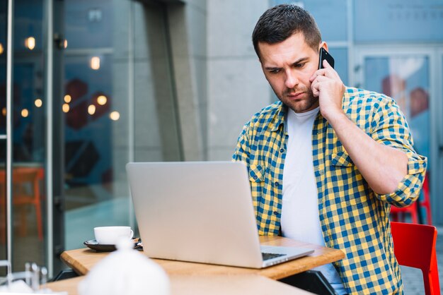 Verwirrter Mann, der Telefongespräch im Café hat