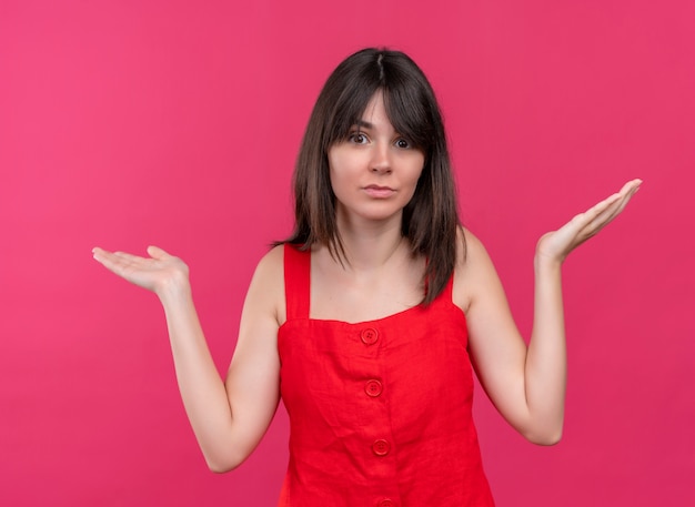 Verwirrtes junges kaukasisches Mädchen hält beide Hände auf lokalisiertem rosa Hintergrund