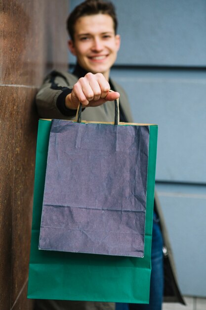 Verwischen Sie den hübschen jungen Mann, der Einkaufstaschen zeigt