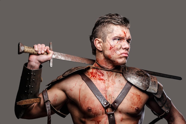 Verwundeter Gladiator mit muskulösem Körper, der ein Schwert hält