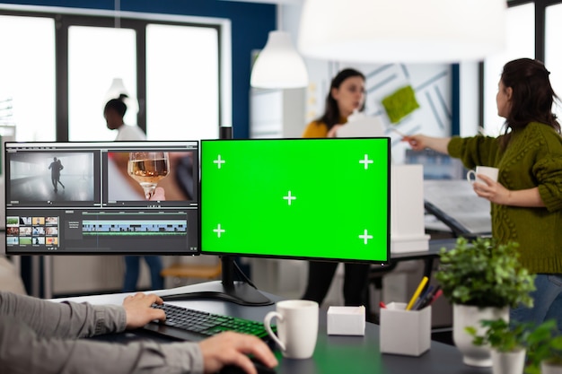 Videomacher, der Filme mit Postproduktionssoftware bearbeitet, die in der Kreativagentur am PC mit grünem Bildschirm, Chroma-Key, isolierter Anzeige arbeitet