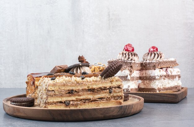 Viel Stück Kuchen mit Keksen auf Holzschneidebrett.