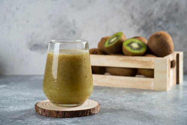 Viele Kiwis in einem Holzkorb mit einer Glasschale Saft.