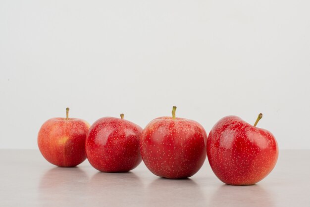 Viele rote Äpfel auf weißem Tisch.