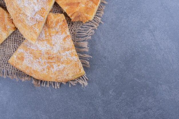 Viele Stücke leckeren Kuchens mit Zuckerpulver auf einem Sack