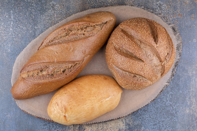 Vielzahl von Brotsorten auf einem Holzbrett auf Marmoroberfläche