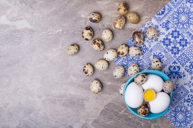 Vielzahl von Eiern in einer blauen Tasse und auf dem Boden.