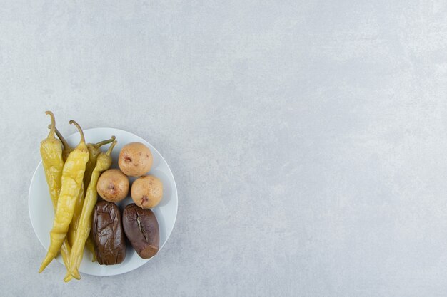 Vielzahl von fermentiertem Gemüse und Früchten auf weißem Teller.