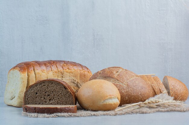 Vielzahl von hausgemachtem Brot auf Sackleinen mit Weizen. Hochwertiges Foto