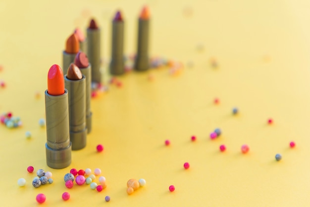 Kostenloses Foto vielzahl von lippenstiftfarbtönen vereinbarte in der reihe auf gelbem hintergrund