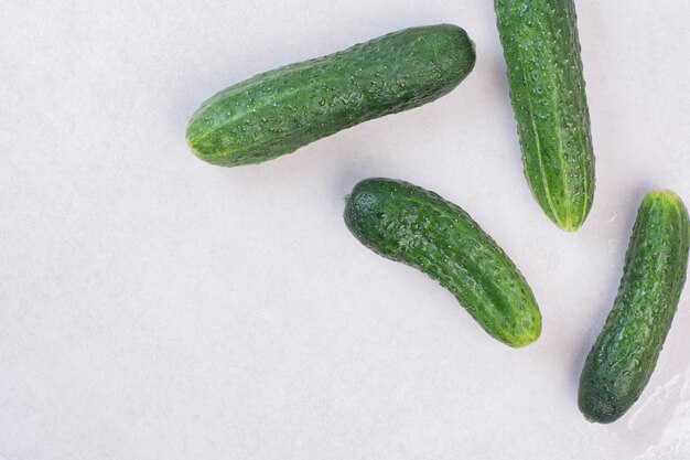 Vier frische Gurken auf weißem Tisch.