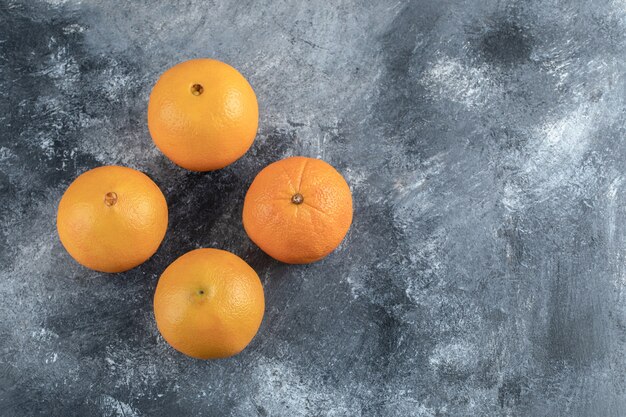 Vier leckere Orangen auf Marmortisch.