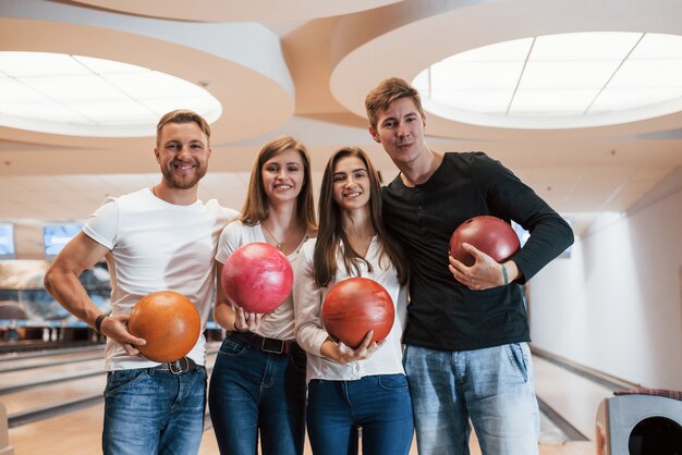 Vier positive Menschen. Junge fröhliche Freunde haben an ihren Wochenenden Spaß im Bowlingclub