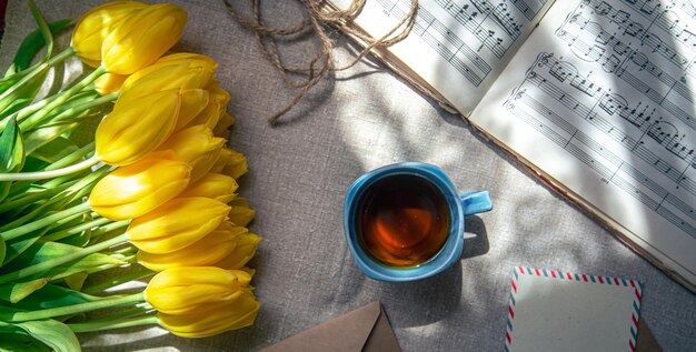 Vintage-Komposition mit einer Tasse Tee Tulpen und Notizen flach gelegt