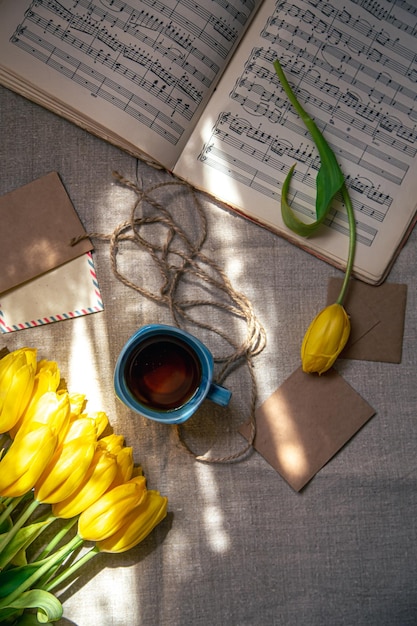 Vintage-komposition mit einer tasse tee tulpen und notizen flach gelegt