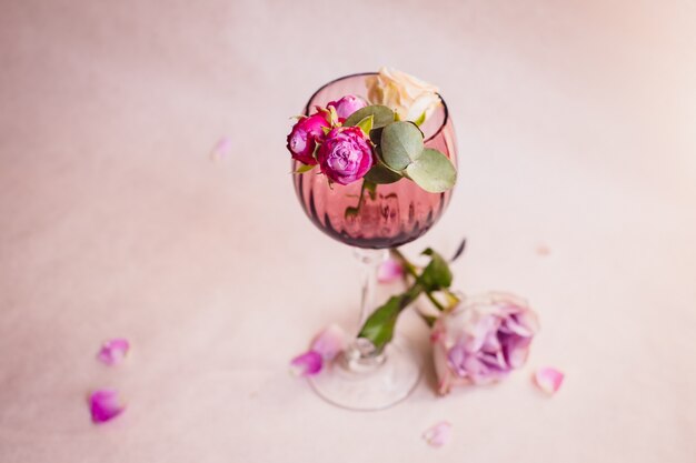 Violette Hydrangea liegt unter Glas mit rosa Rosenknospen