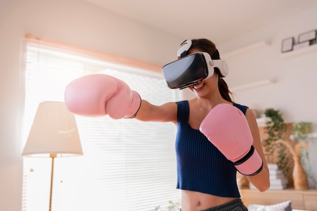Virtual Metaverse Augmented Reality asiatische erwachsene Frau, die Boxen im VR-Headset Aerobic-Training für Boxpunsch in virtueller Realität im Wohnzimmer zu Hause trainiert