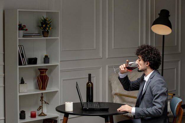Virtuelle Liebe, hübscher, süßer Kerl im Anzug mit Wein auf einem Ferncomputer-Date, der Wein trinkt