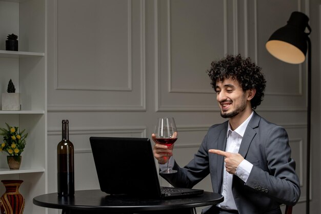 Virtuelle Liebe, hübscher, süßer Kerl im Anzug mit Wein bei einem Ferncomputer-Date, der Rotwein trinkt