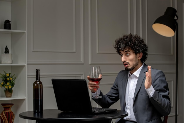 Virtuelle Liebe, hübscher, süßer Kerl im Anzug mit Wein bei einem fernen Computerdate aufgeregt