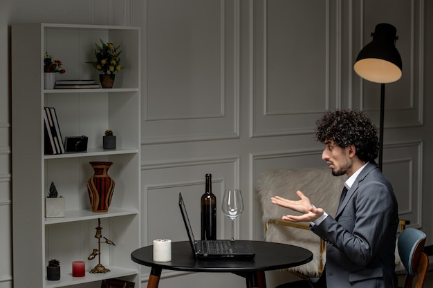 Virtuelle Liebe, hübscher, süßer Kerl in einem Anzug mit Wein auf einem entfernten Computerdatum, der mit den Händen winkt