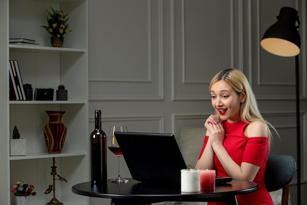 Virtuelle Liebe süßes blondes Mädchen im roten Kleid am Ferndatum mit Weinlächeln