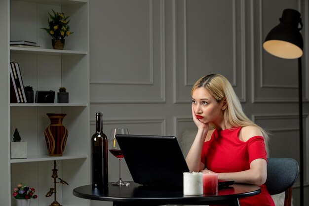 Virtuelle Liebe süßes Mädchen in rotem Kleid am Ferndatum mit Wein, der nach oben schaut