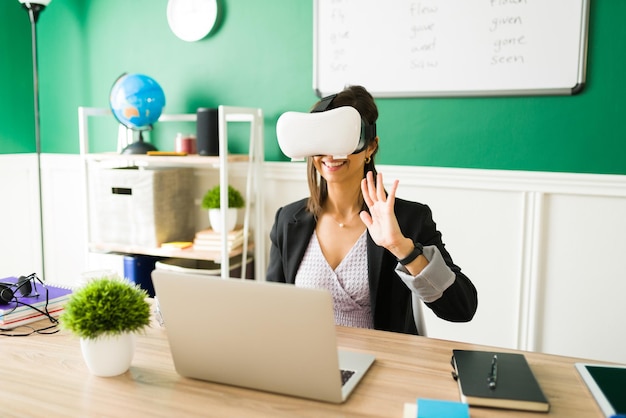 Virtueller Klassenraum. Aufgeregter junger Lehrer, der ein VR-Headset trägt und eine Online-Lektion durch virtuelle Realität gibt