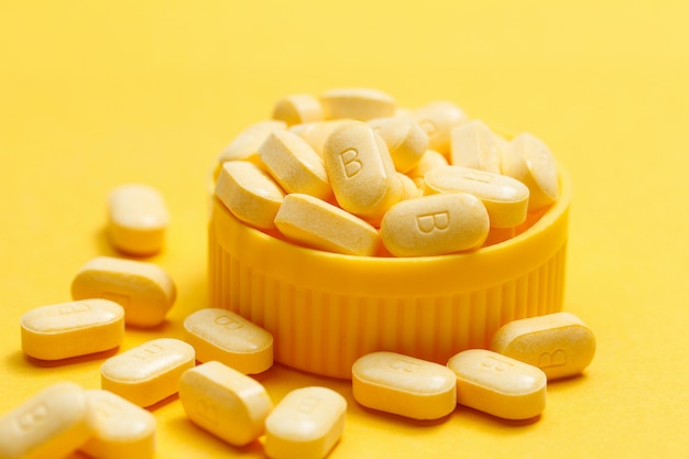 Vitamin B Tabletten auf gelbem Hintergrund