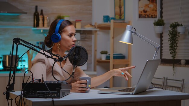 Vlogger spricht live mit einem Follower über ein professionelles Mikrofon mit Kopfhörern. Kreative Online-Show On-Air-Produktion Internet-Broadcast-Host-Streaming von Live-Inhalten, Aufzeichnung digitaler sozialer Medien