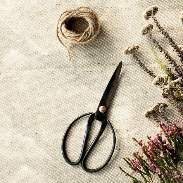 Vogelperspektive von Scissor und von Blumen auf Sackleinenhintergrund