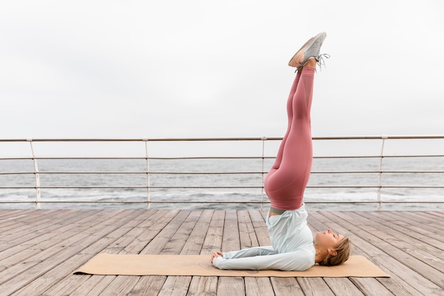 Voll erschossene Frau beim Yoga auf der Matte