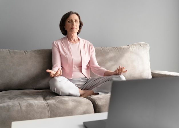 Voll erschossene Frau, die auf der Couch meditiert