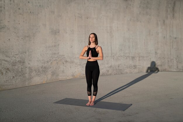 Voll erschossene Frau, die auf Yogamatte steht