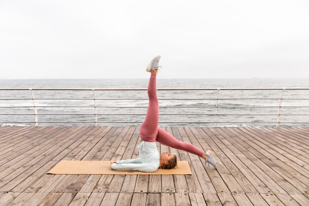 Voll erschossene Frau, die draußen Yoga macht