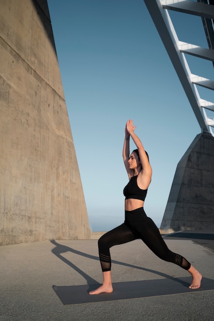 Voll erschossene Frau, die draußen Yoga macht