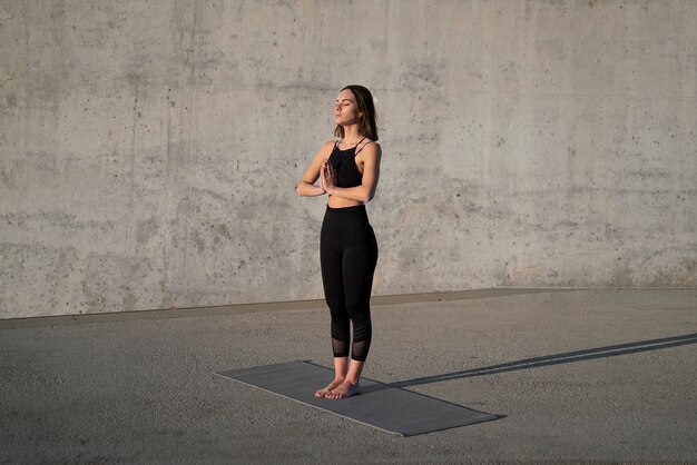 Voll erschossene Frau, die Yoga mit Matte macht