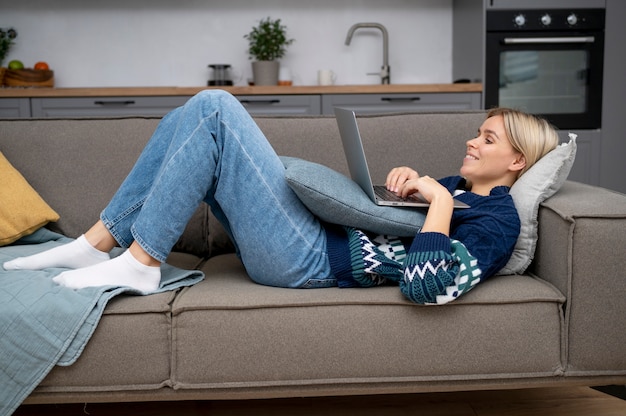 Voll erschossene Frau mit Laptop auf der Couch