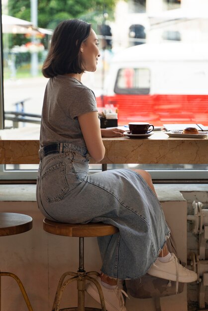 Voll erschossene Frau sitzt mit Kaffee