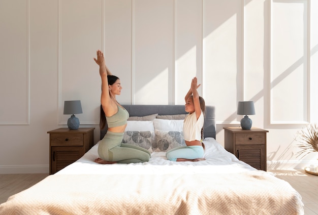 Kostenloses Foto voll erschossene frau und mädchen, die im bett meditieren