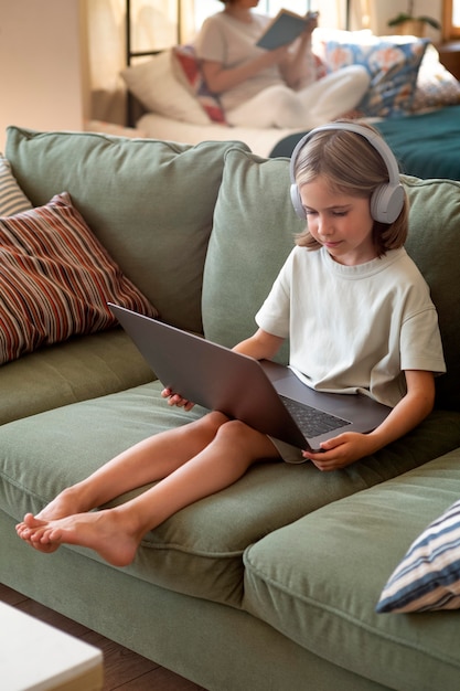 Voll erschossenes Mädchen mit Laptop auf der Couch