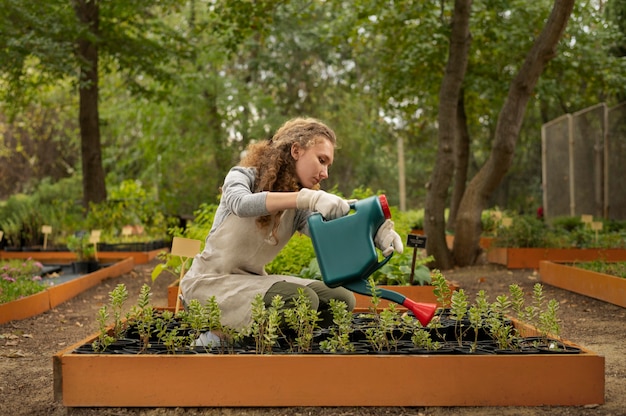 Voll geschossene Frau gießt Gartenpflanzen