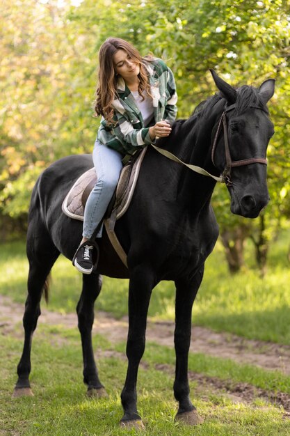 Voll geschossene Frau reitet auf einem Pferd