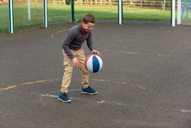 Voll geschossenes Kind, das draußen mit Ball spielt