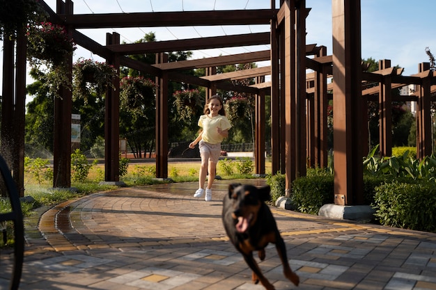 Voll geschossenes Mädchen, das mit Hund läuft