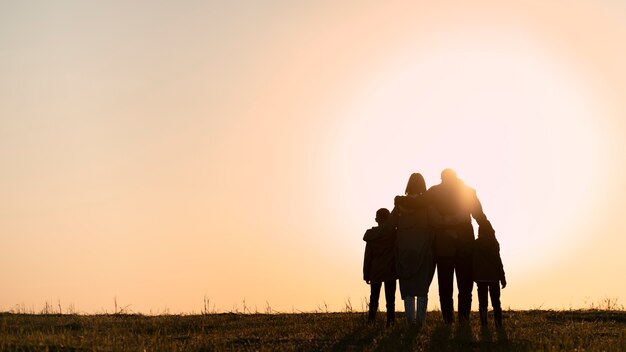 Vollbild-Familiensilhouette, die Spaß bei Sonnenuntergang hat